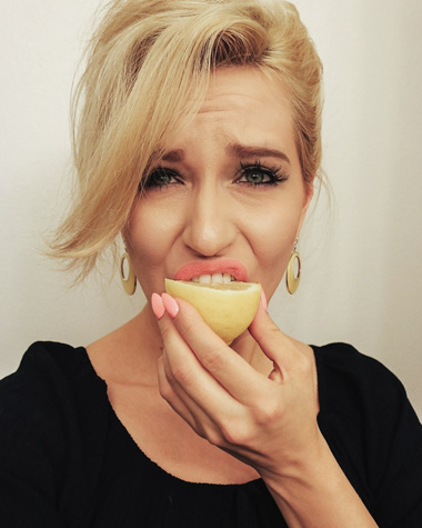 Blonde Frau beisst in eine Zitrone